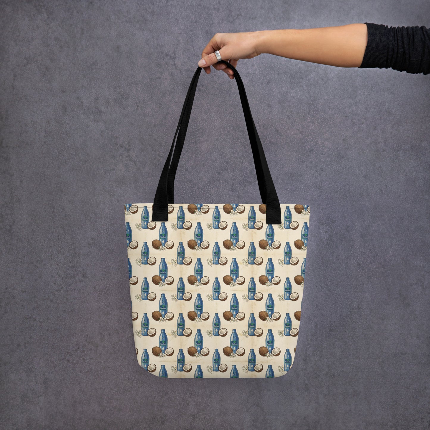 Hand holding tote bag with tail malish coconut oil inspired print